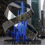 Infinite Ribbon contemporary stainless steel architectural sculpture by FORMA Sculptures, featuring a flowing ribbon form with integrated blue lighting for landmark public art in urban environments.
