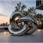 Trinity Flow contemporary stainless steel knot sculpture by FORMA Sculptures, featuring intertwined polished forms that create a landmark public art installation for luxury developments, corporate headquarters, and urban plazas.